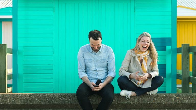 Two people using mobile devices outside