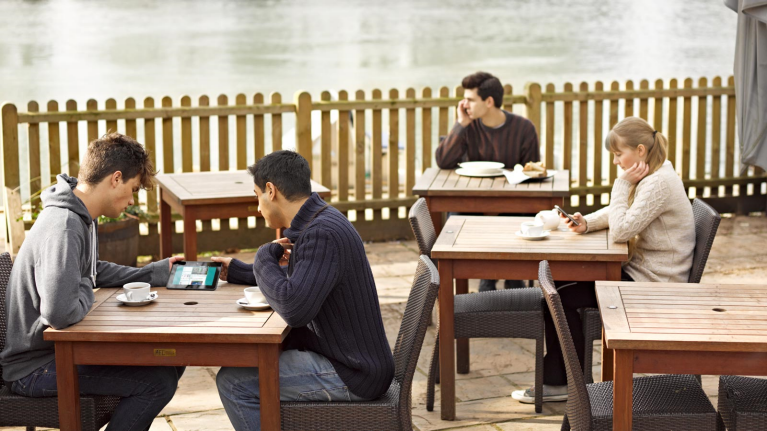 Employees using their devices outside at a coffee shop representing retail data insight at EE Business