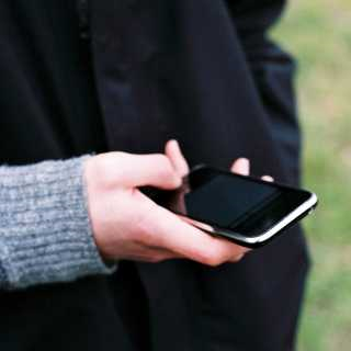 The hand of woman who is holding her EE Business phone. 