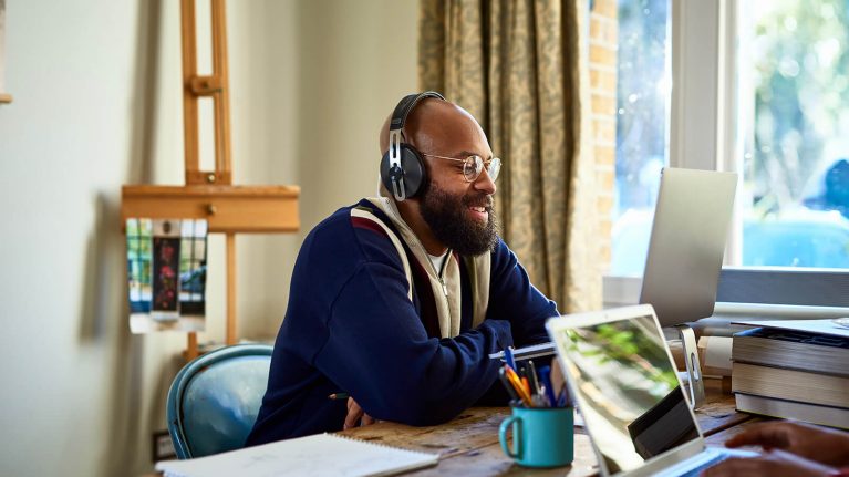 A man working from home on a laptop while his young son asks a question