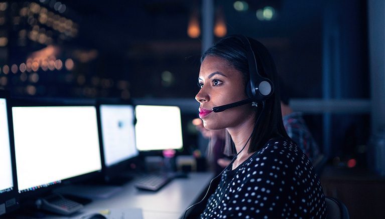 Woman with headset looking at computer screen