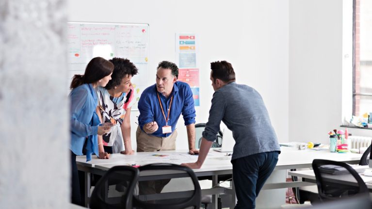 People standing talking around a desk in an office