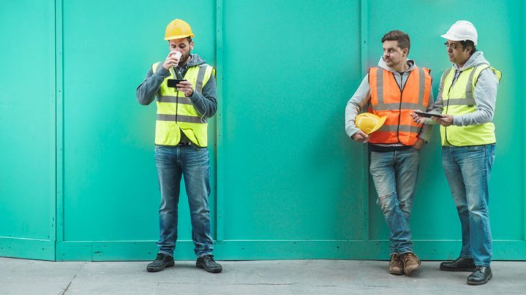 Workmen standing outside with phones
